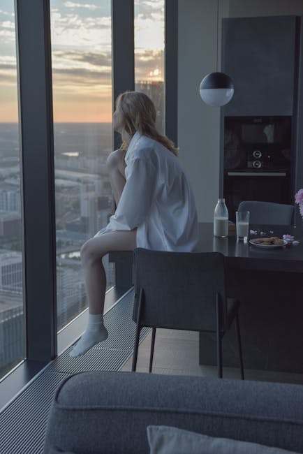A person looking out a window at a peaceful sunrise